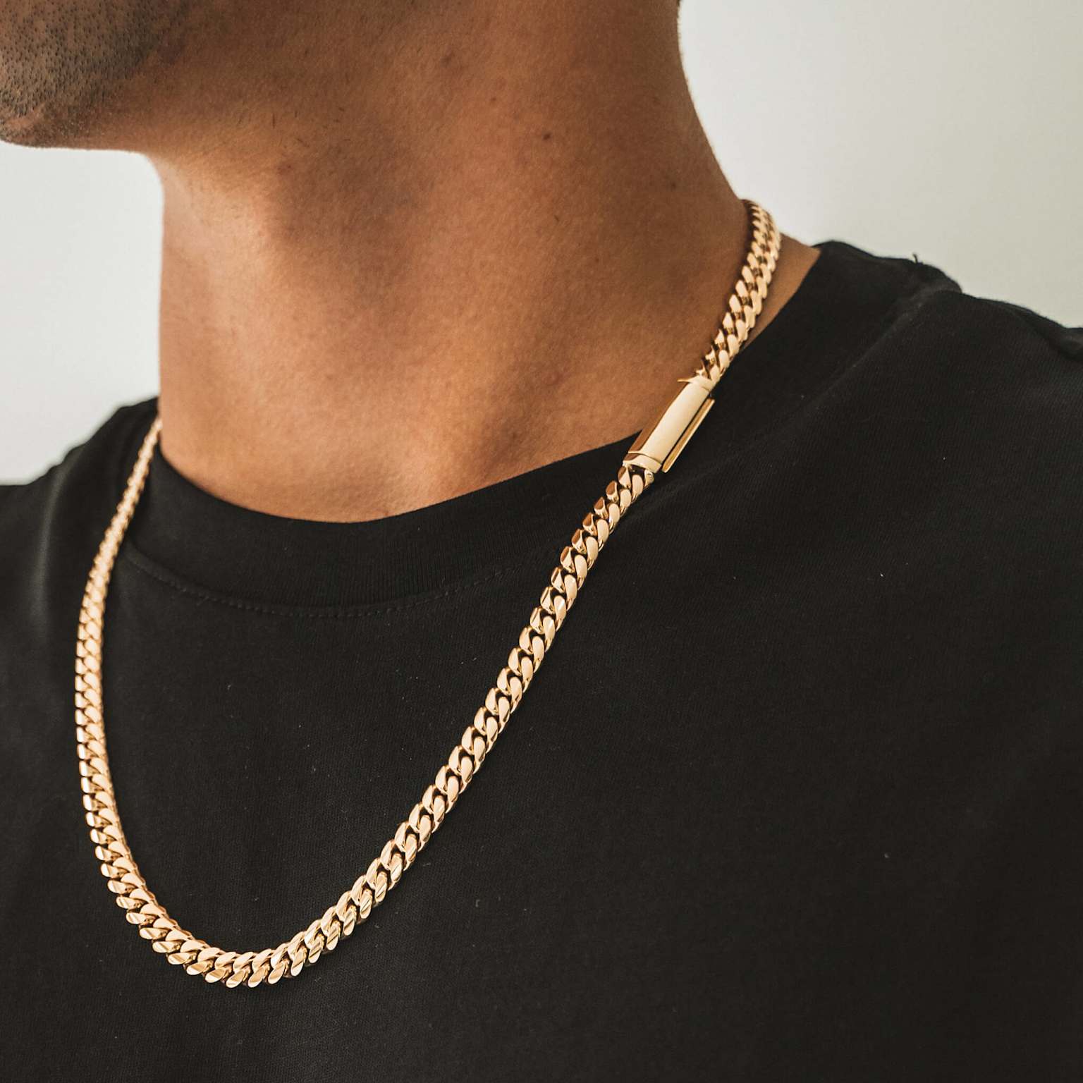 A polished gold Cuban link chain with a sleek, integrated clasp worn by a person
