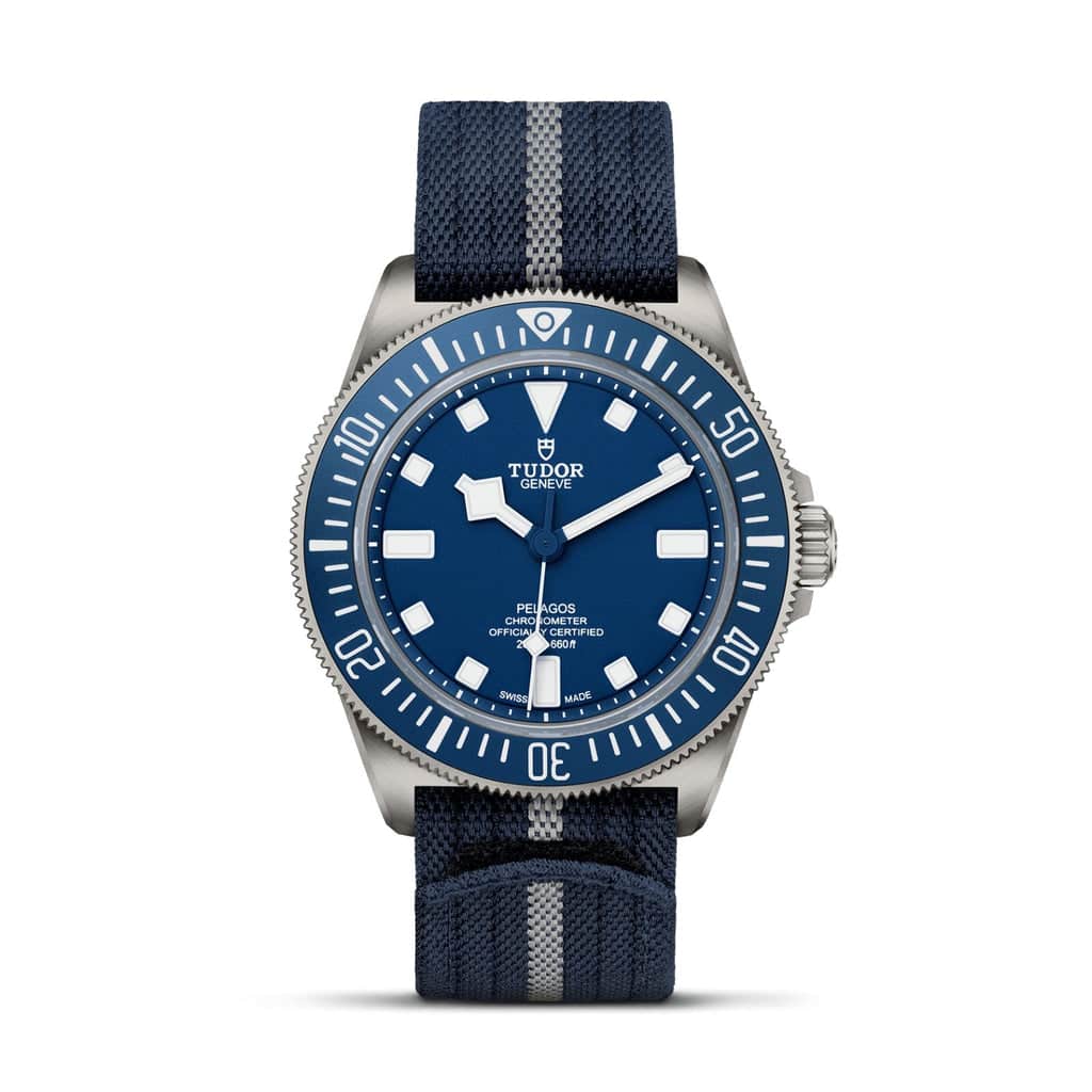 A close-up view of the Tudor Pelagos dive watch with a blue dial, titanium case, and a blue fabric strap