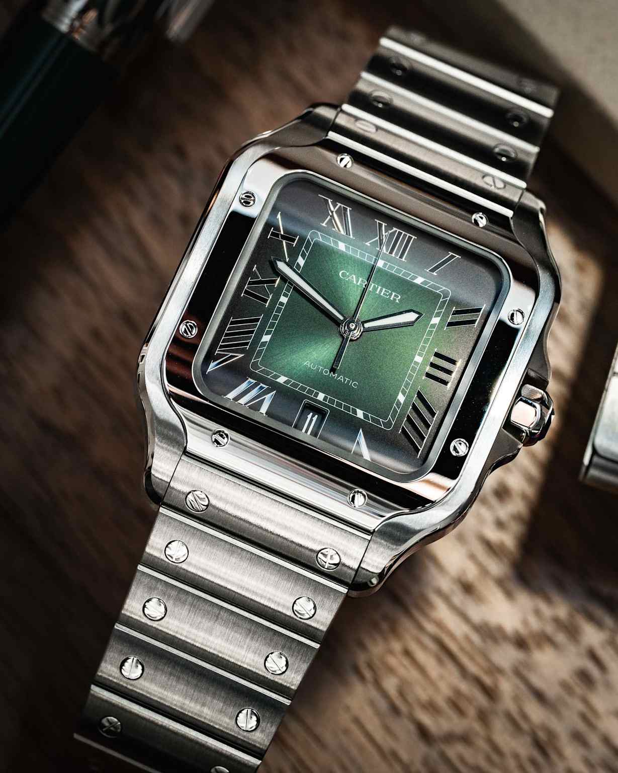 A detailed view of a Cartier Santos de Cartier watch with a green gradient dial and a stainless steel bracelet