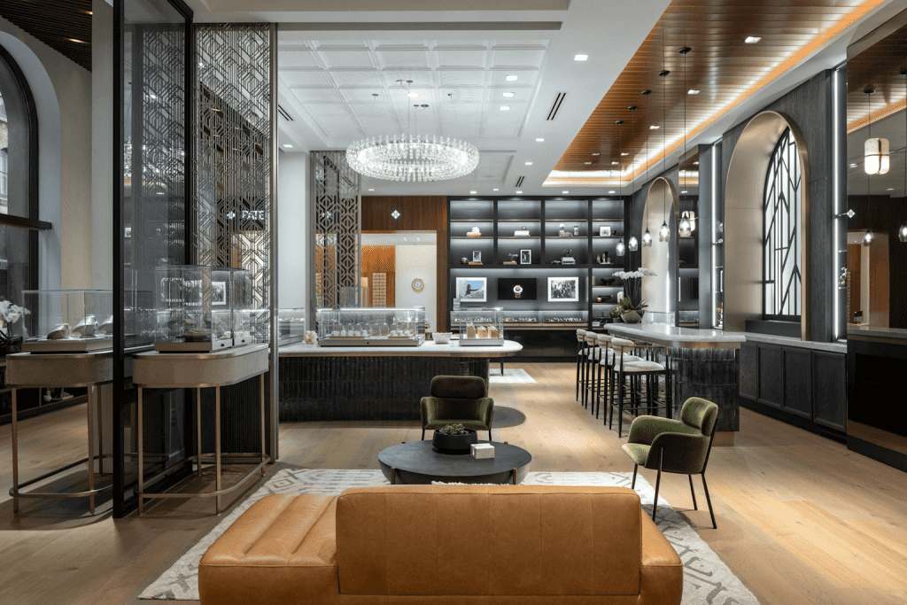 Elegant luxury watch boutique with modern display cases, chandelier, and seating area.