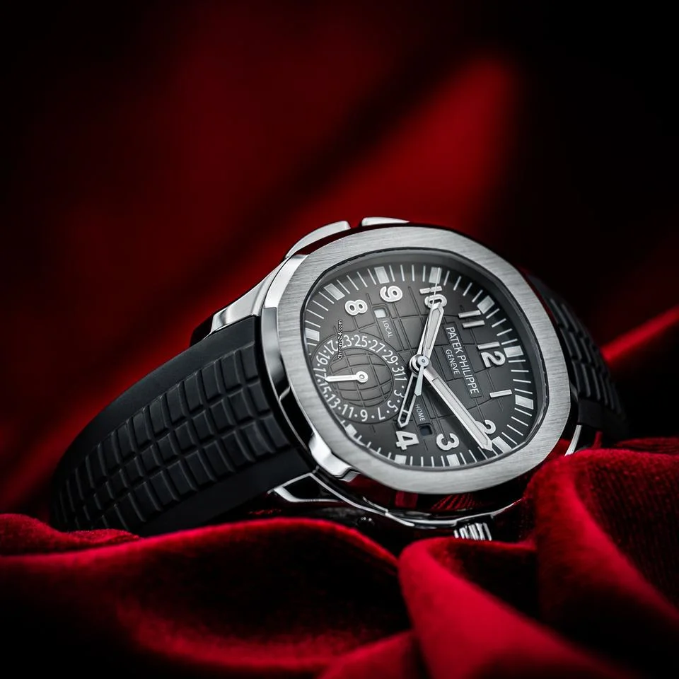Patek Philippe Aquanaut Travel Time watch with dual time display and black rubber strap on red velvet
