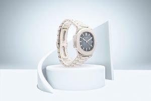 Patek Philippe Nautilus with grey dial and white gold case displayed on a minimalist white pedestal.