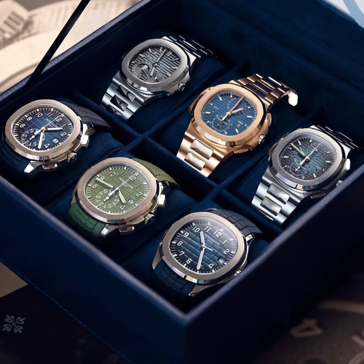 Luxury Patek Philippe Nautilus watches displayed in a velvet-lined collector's box.