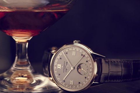 Vacheron Constantin moonphase watch with leather strap beside a glass of cognac.