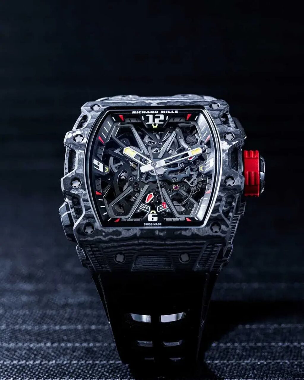 Richard Mille carbon-case skeleton watch with red crown and open-worked dial showcasing complex movement.