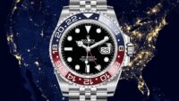 Rolex GMT-Master II Pepsi in Oystersteel with red and blue bezel and black dial against night world map backdrop.